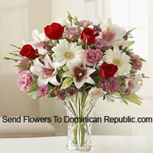 Красные розы, розовые гвоздики, белые герберы и белые лилии с другими разнообразными цветами в стеклянной вазе